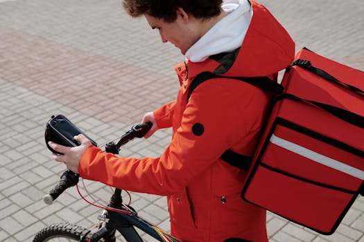 Food delivery cyclist checking smartphone while working. Urban lifestyle and technology.